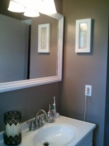 bathroom remodeling job with brown walls and white porcelain sink fixture, white picture frame on wall and electric toothbrush holder on sink top